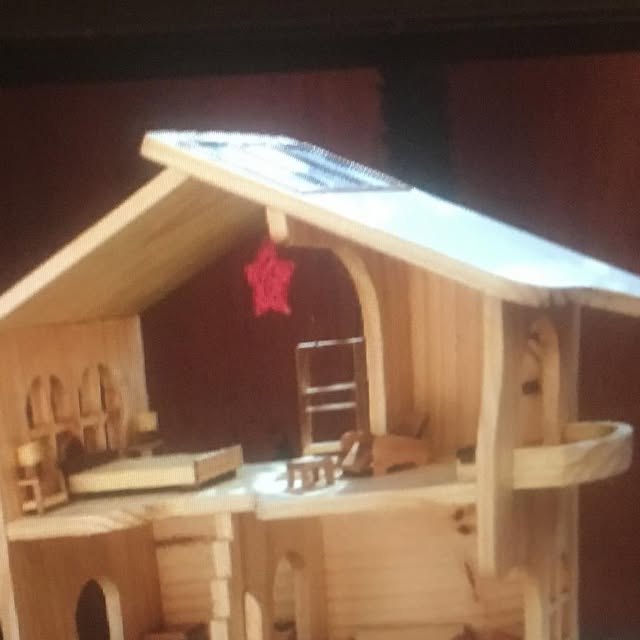 Casa de boneca em madeira, mobiliada por dentro, com escada e telhado.